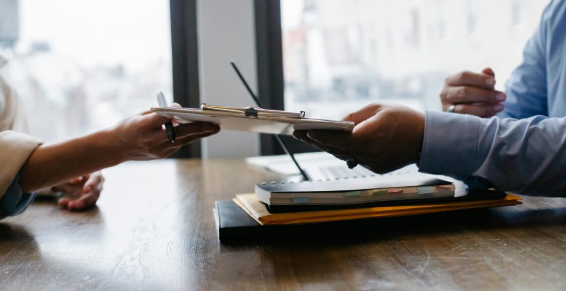 A women handing over a clipboard to another women to sign