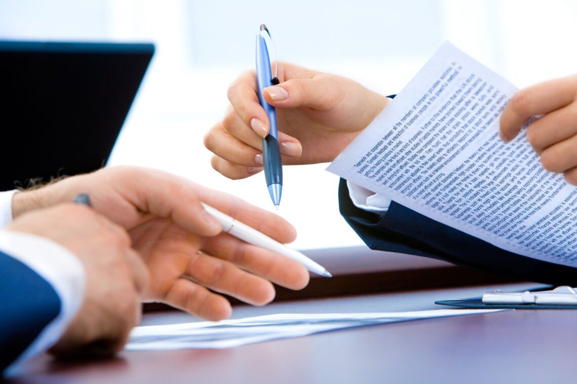 Hands shown signing papers and gesturing with pens.